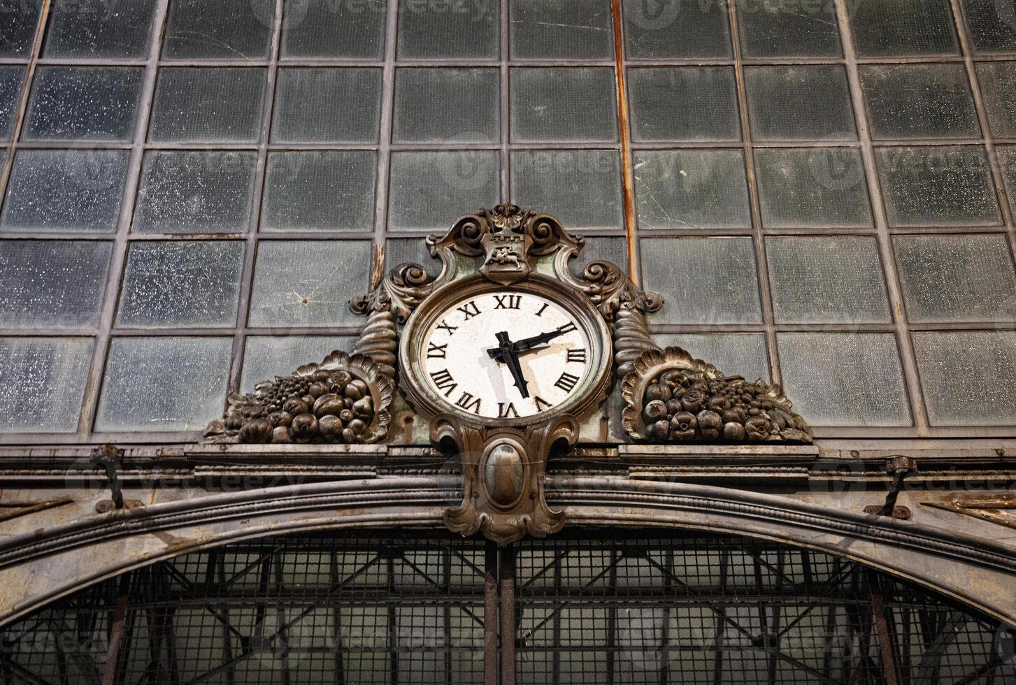 Old clock hanging on ancient market wall. photo