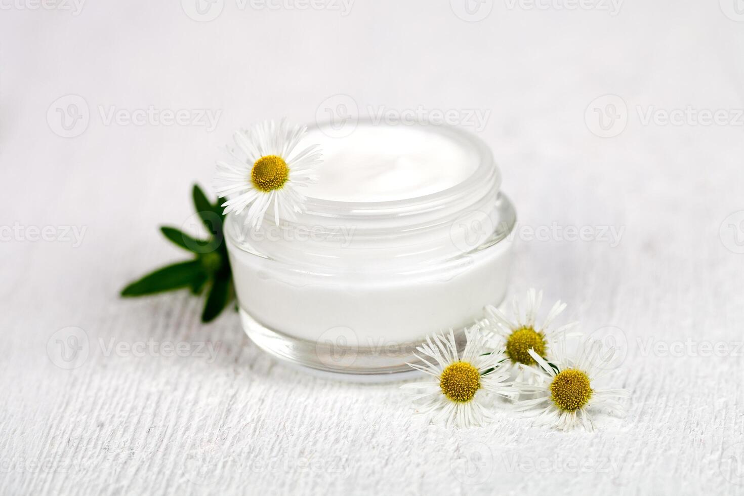 container with cream and chamomiles photo
