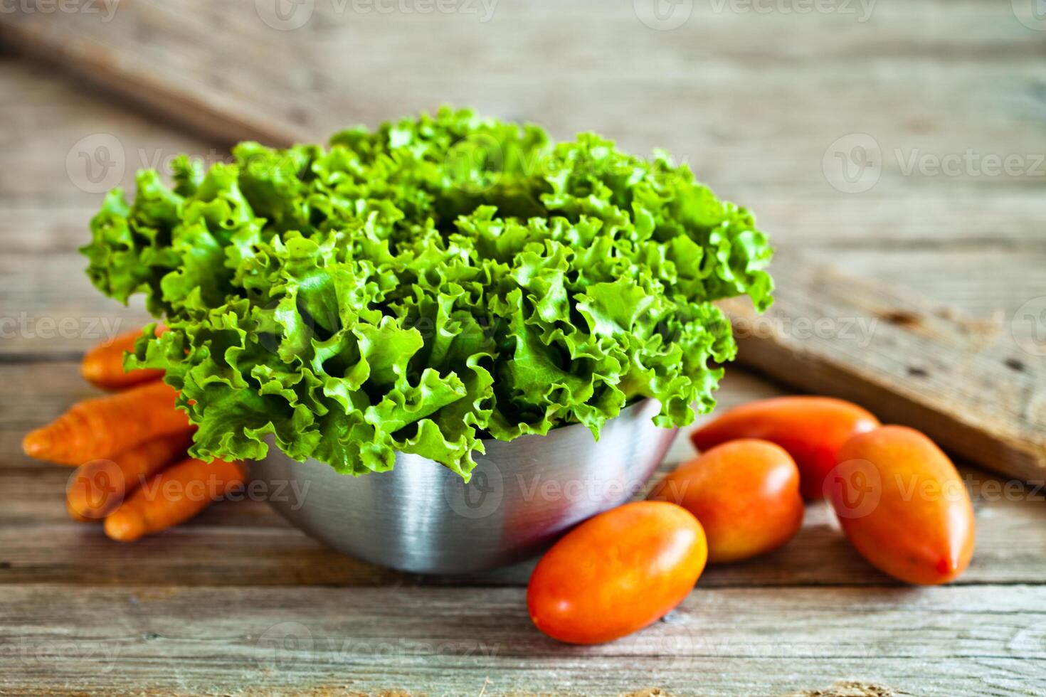 lettuce salad in metal bowl, tomatoes and carrots photo