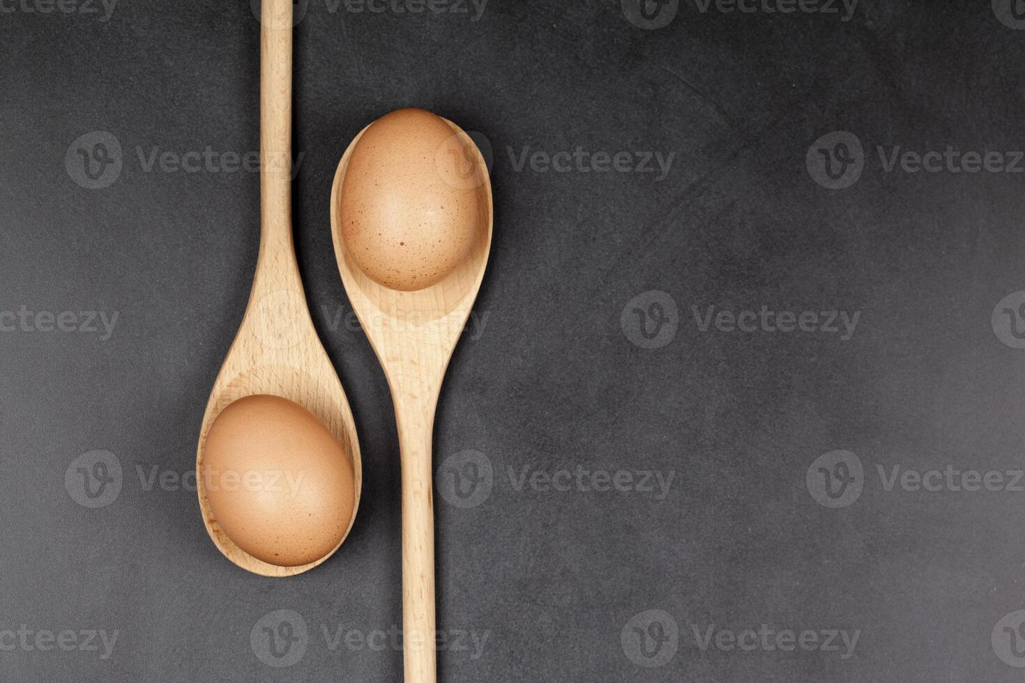 Eggs in wooden spoons. Kitchen utensil for cake, pastry or cookies on backboard background. photo