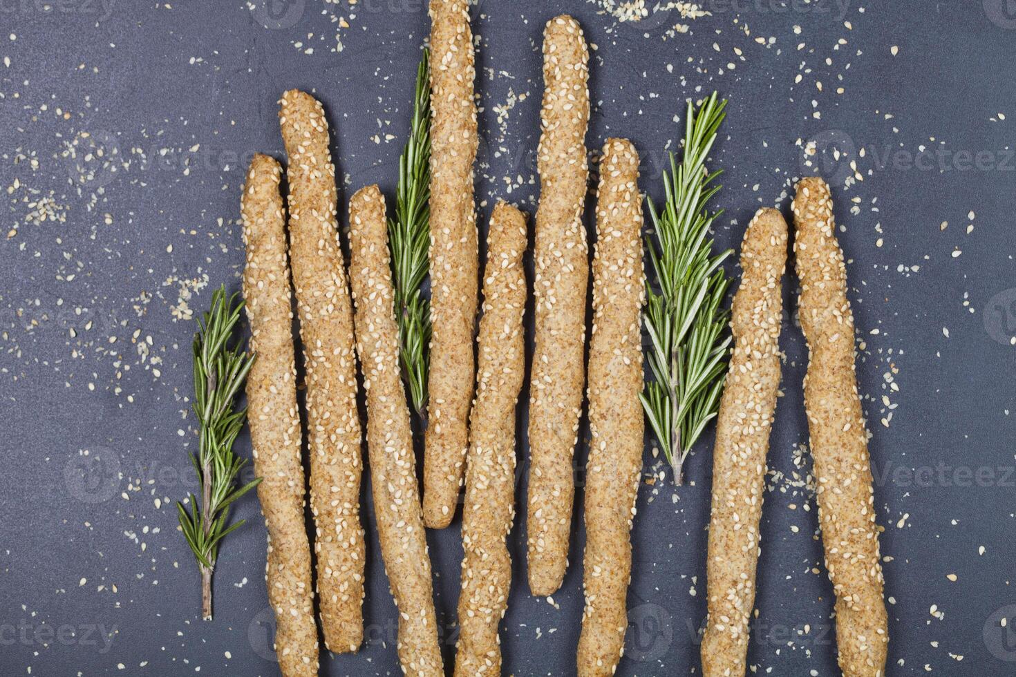 Italian grissini or salted bread sticks with sesame and rosemary herb on black board background. photo