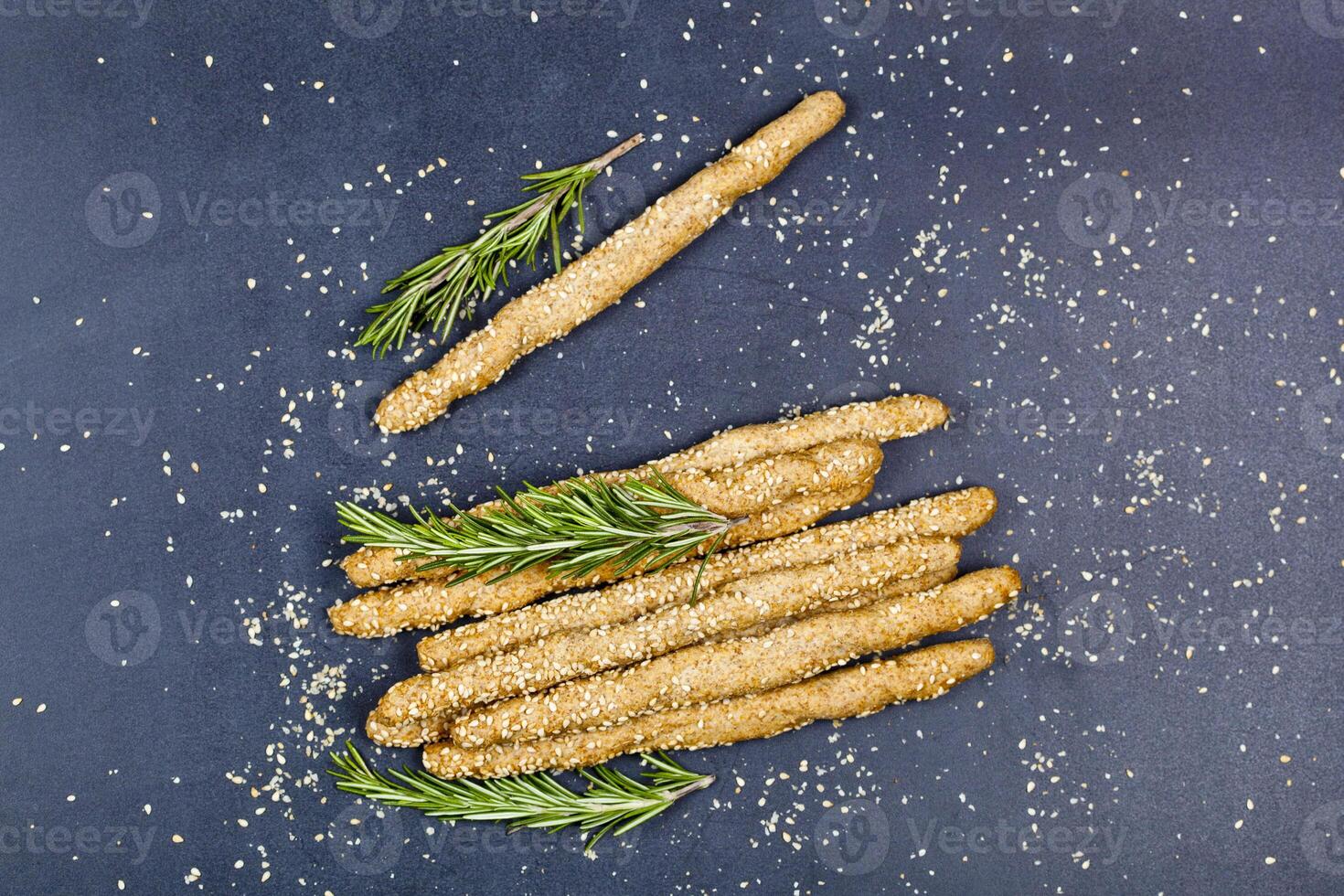 Italian grissini or salted bread sticks with sesame and rosemary herb on black board background. photo