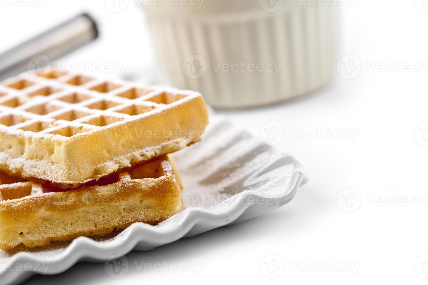Belgium waffers with sugar powder on ceramic plate and strainer on white table. photo