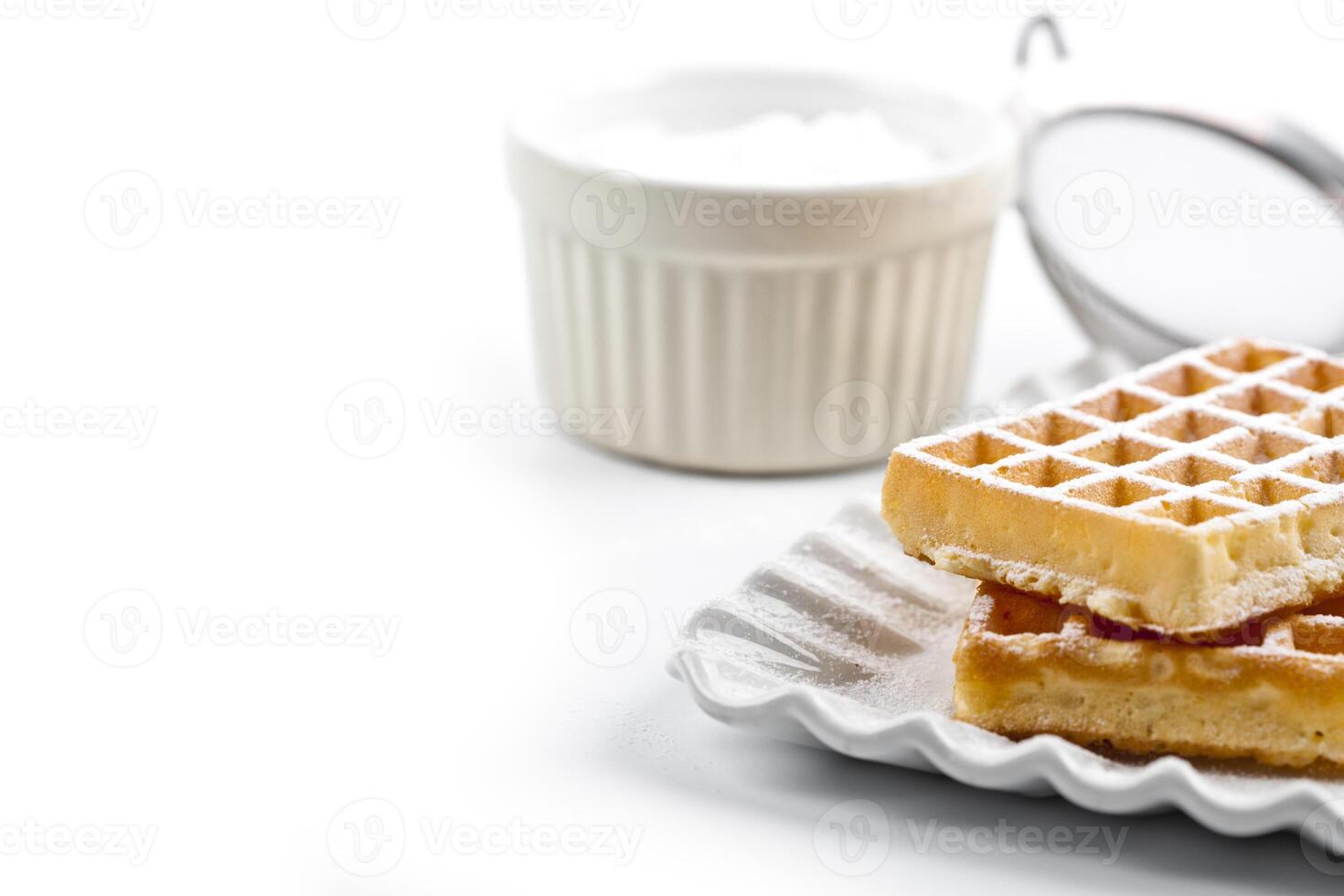 Belgium waffers with sugar powder on ceramic plate and strainer on white table. photo