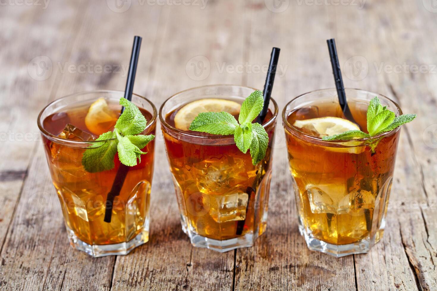 Traditional iced tea with lemon, mint leaves and ice cubes in glasses on rustic wooden table. photo