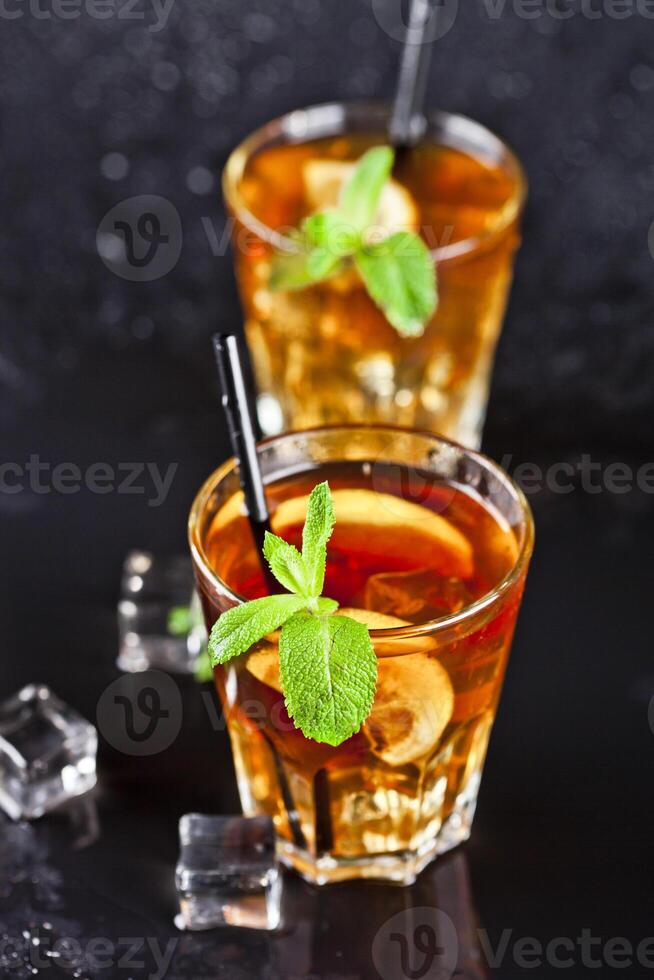 Two glasses with cold traditional iced tea with lemon, mint leaves and ice cubes. photo