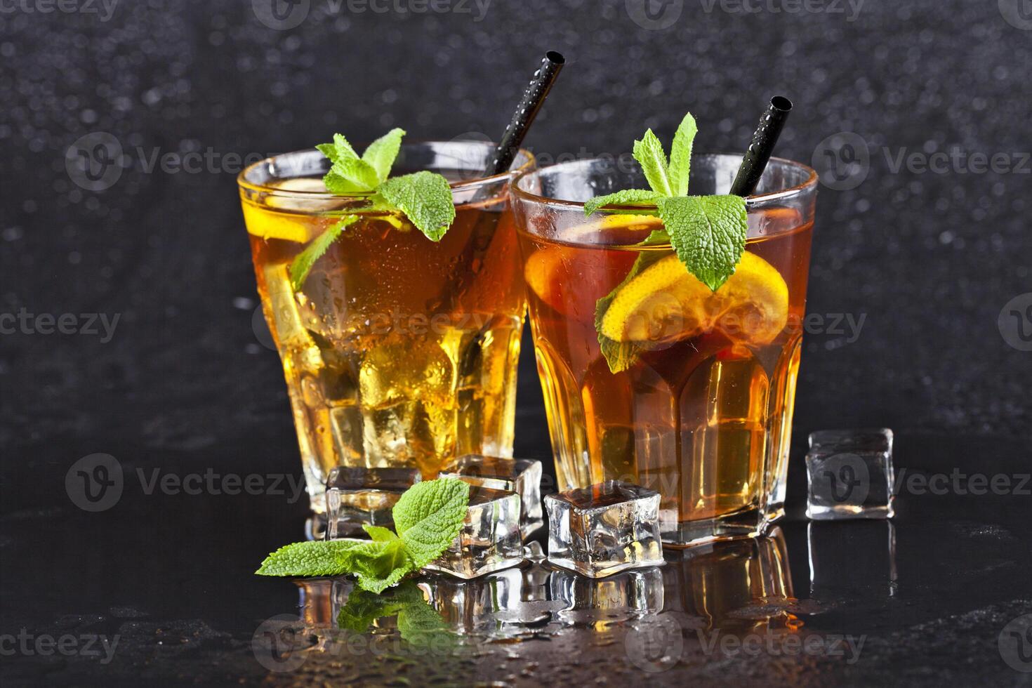 Two glasses with cold traditional iced tea with lemon, mint leaves and ice cubes. photo