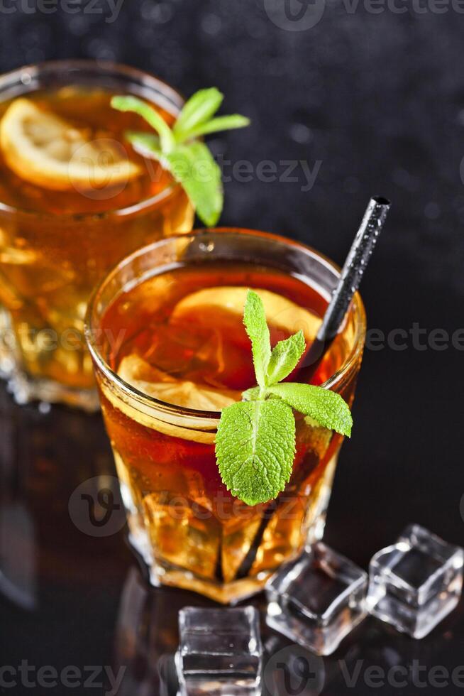 Two glasses with cold traditional iced tea with lemon, mint leaves and ice cubes. photo