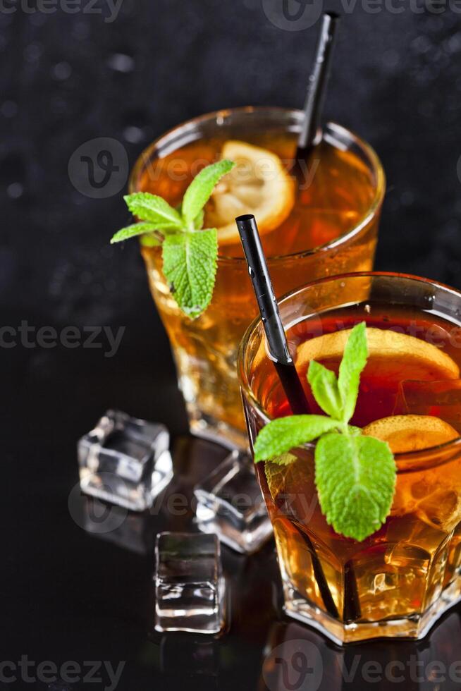 Two glasses with cold traditional iced tea with lemon, mint leaves and ice cubes. photo