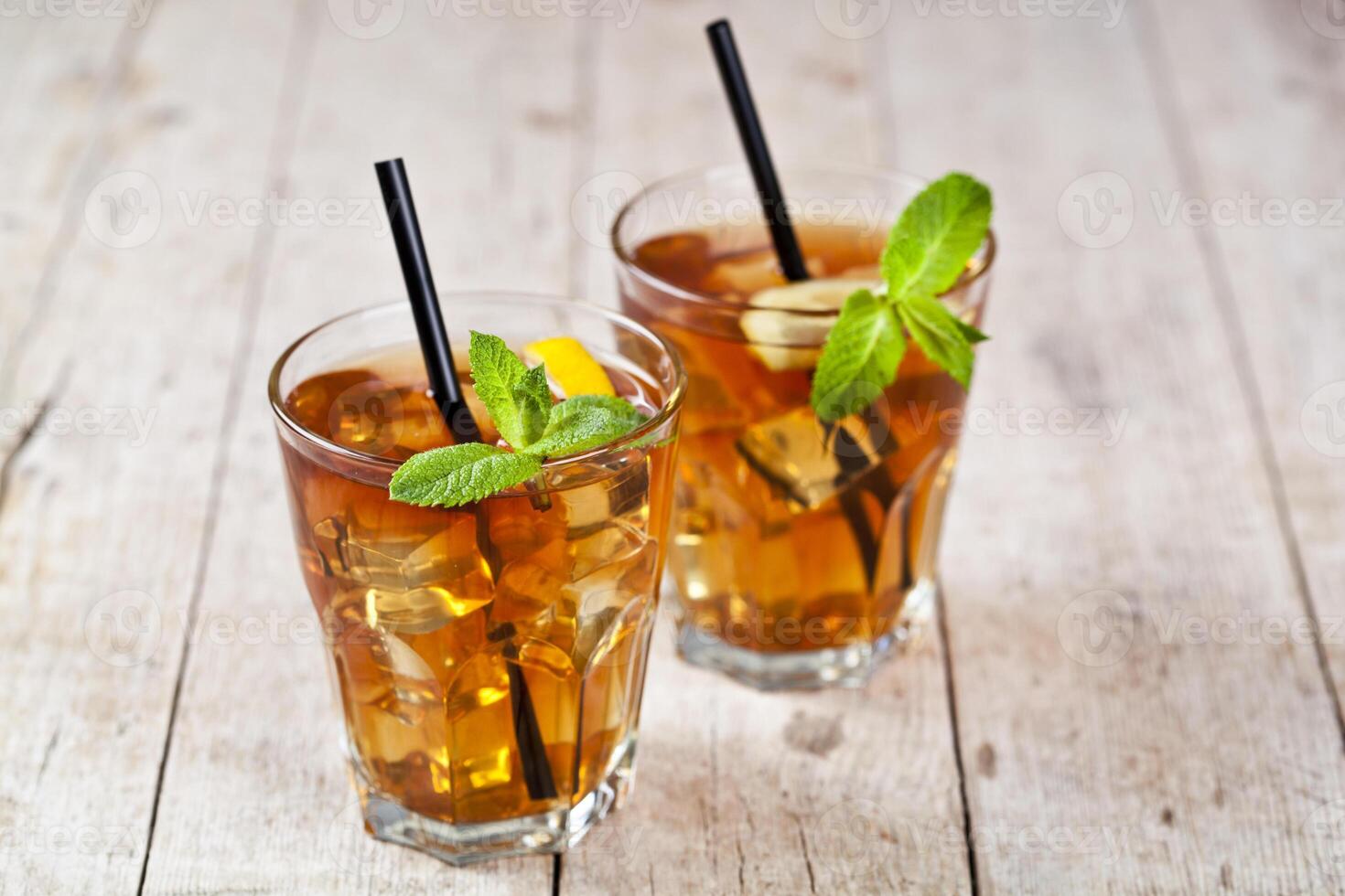 Traditional iced tea with lemon, mint leaves and ice cubes in two glasses on rustic wooden table. photo