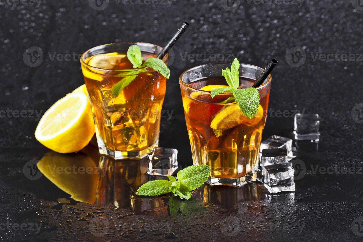 Two glasses with cold traditional iced tea with lemon, mint leaves and ice cubes photo