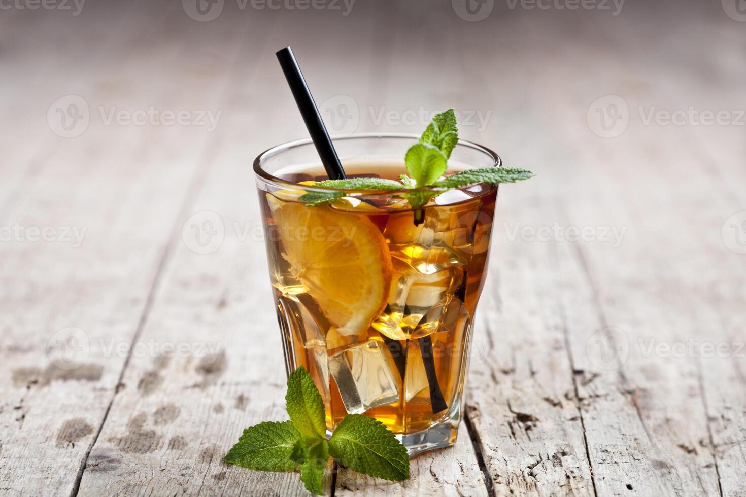 Traditional iced tea with lemon, mint leaves and ice cubes in glass on rustic wooden table. photo
