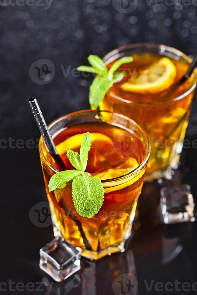 Two glasses with cold traditional iced tea with lemon, mint leaves and ice cubes. photo