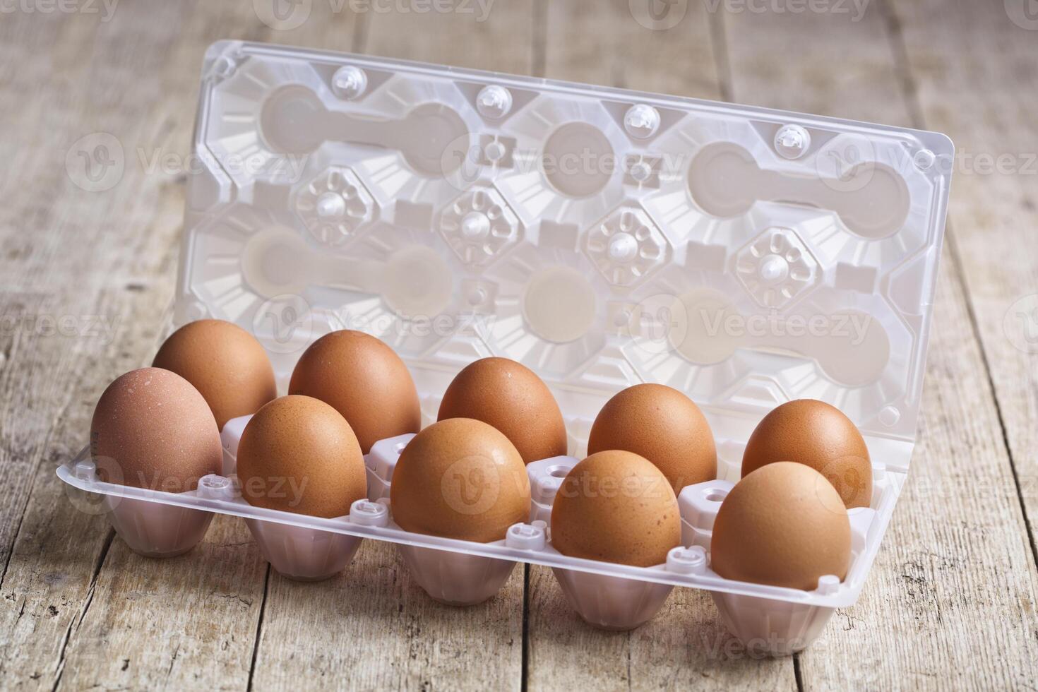 Fresh chicken eggs on plastic container on rustic wooden table. photo