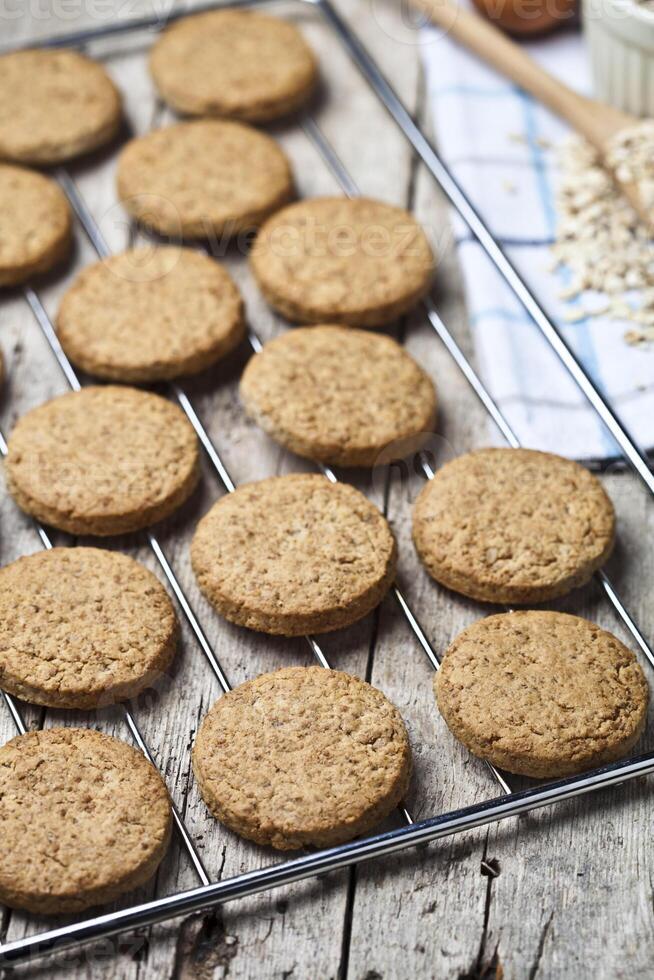 Baking grid with fresh oat cookies on rustic wooden table background and kitchen utensil. photo