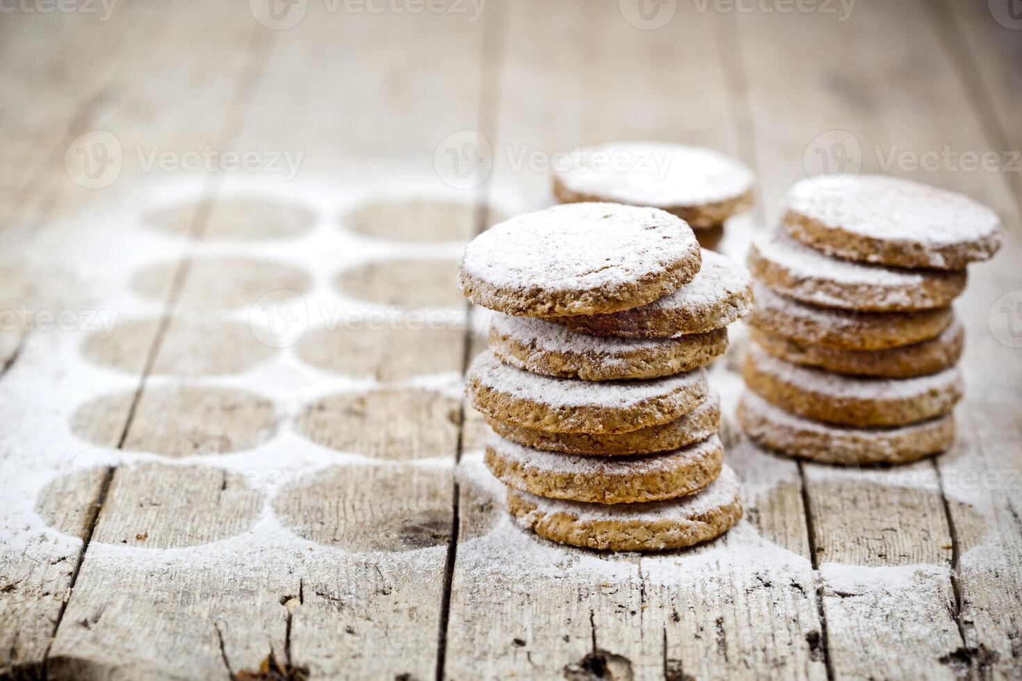 Fresh oat cookies stacks with sugar powder on rustic wooden table background. photo