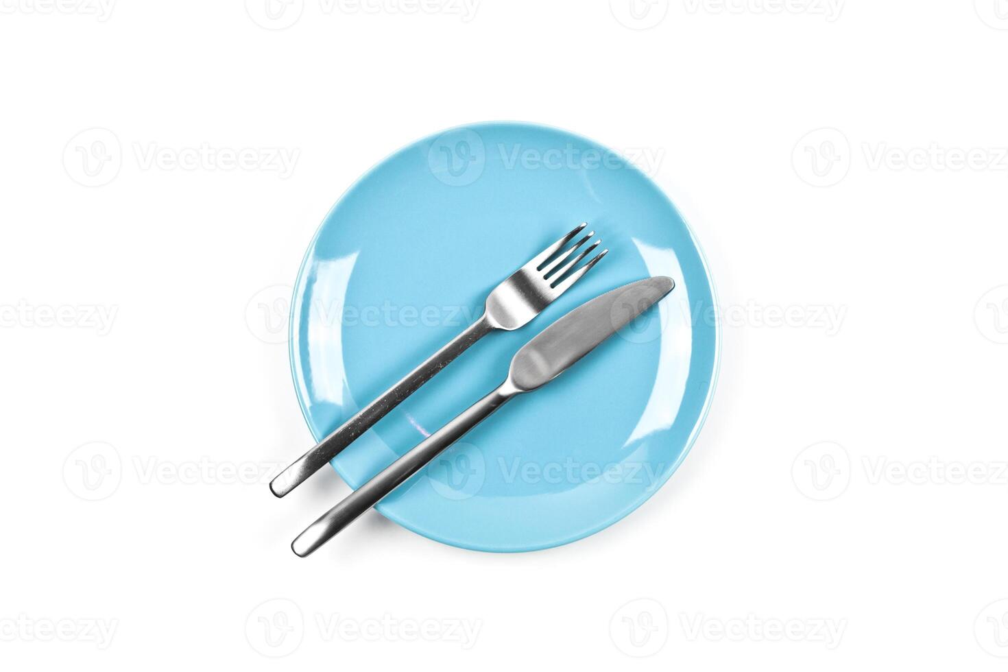 Set of empty blue plate, fork and knife on white background. photo