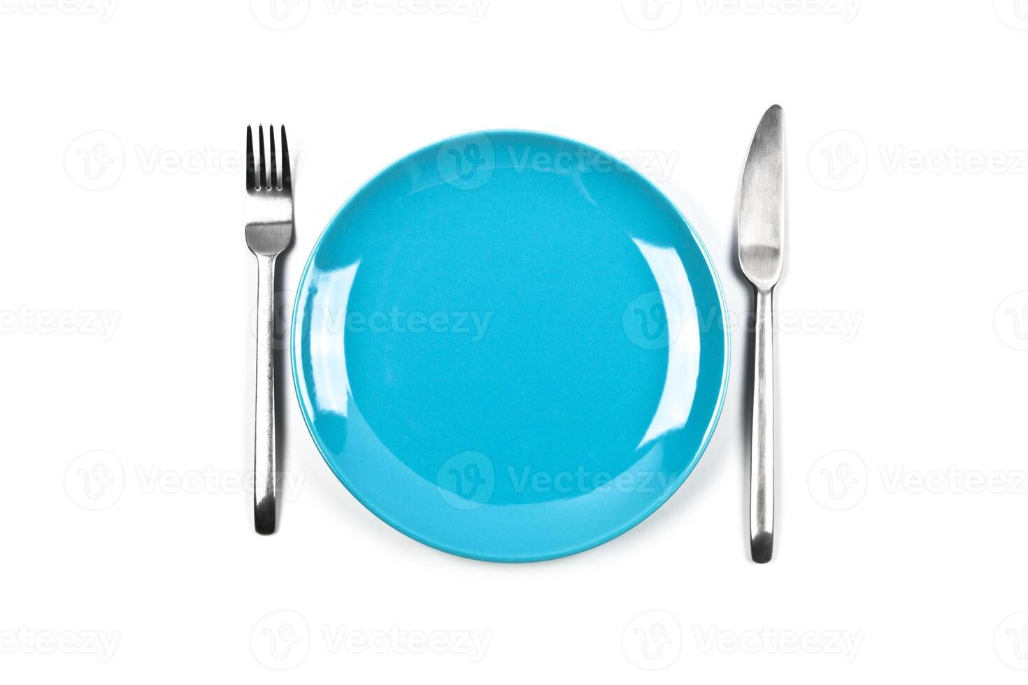 Set of empty blue plate, fork and knife on white background. photo