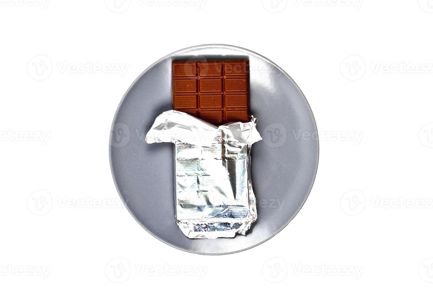 Chocolate bar with foil on grey ceramic plate isolated on white background. photo