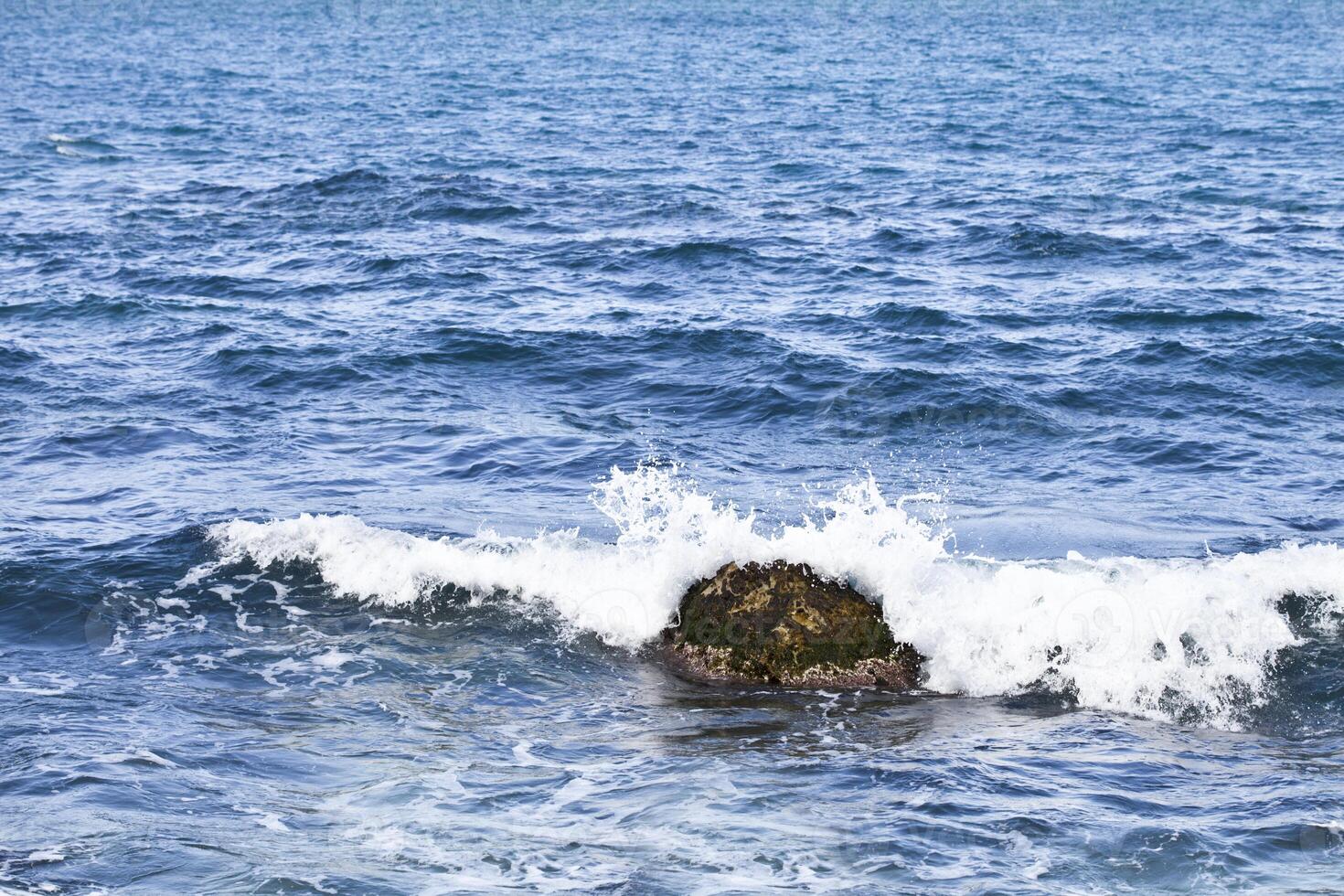 Waving water surface and stone of the Adriatic sea. photo