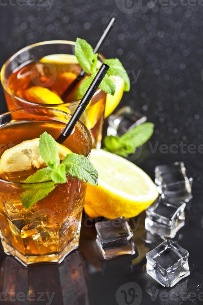 Two glasses with cold traditional iced tea with lemon, mint leaves and ice cubes photo