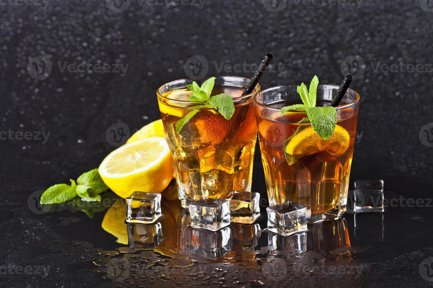Two glasses with cold traditional iced tea with lemon, mint leaves and ice cubes. photo