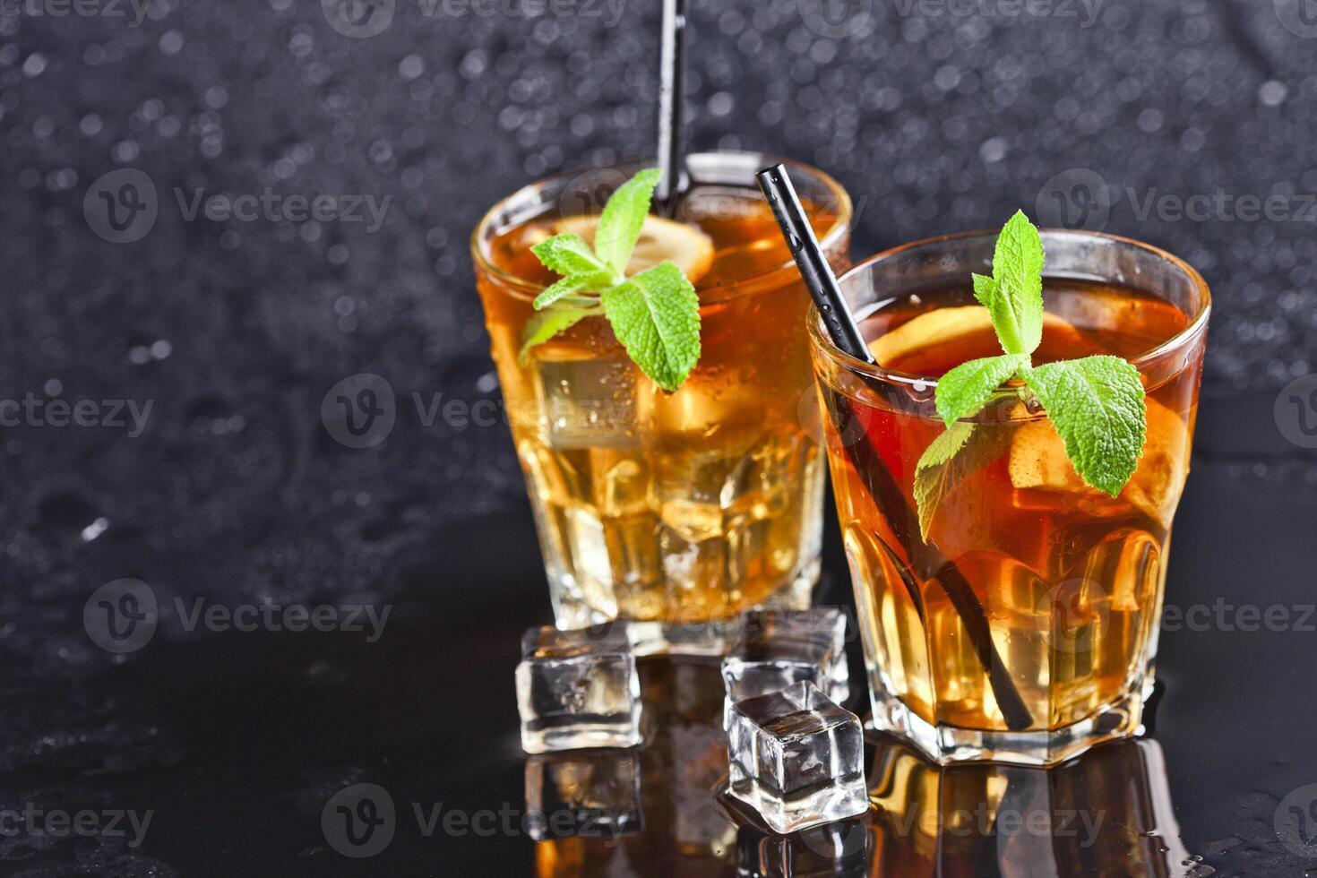 Two glasses with cold traditional iced tea with lemon, mint leaves and ice cubes. photo