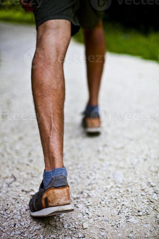 Low angle ground level view with feet of a man on park or forest path. photo