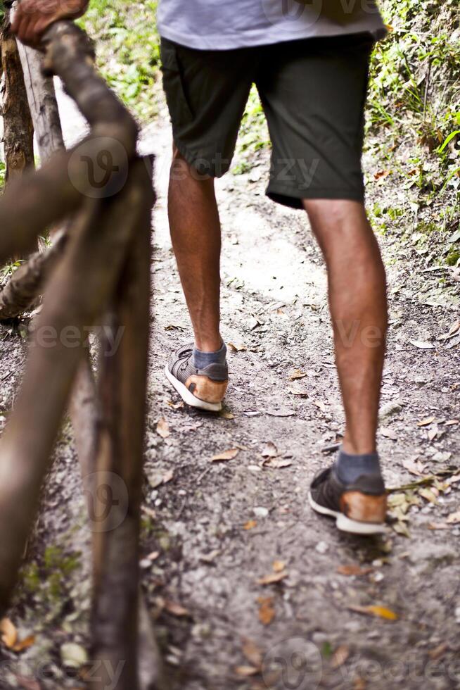 Man's legs on park or forest footpath with handrail closeup. photo