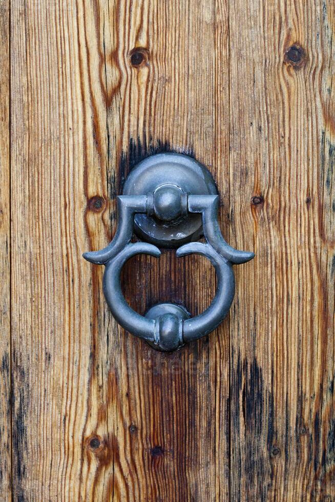 Italian door knocker on old wooden brown background. photo