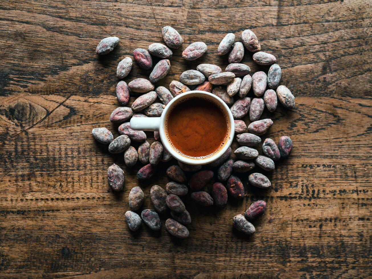 Hot chocolate drink,cocoa drink and natural cocoa powder with brown cocoa beans on a vintage wooden table.Top view photo