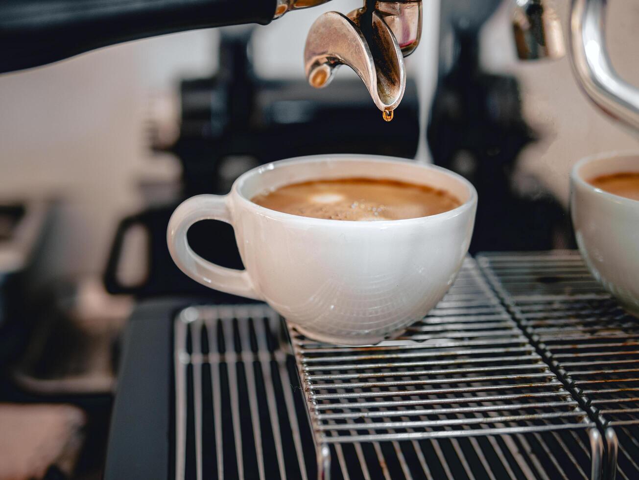 Coffee extraction from the coffee machine with a portafilter pouring coffee into a cup,Espresso poruing from coffee machine at coffee shop photo
