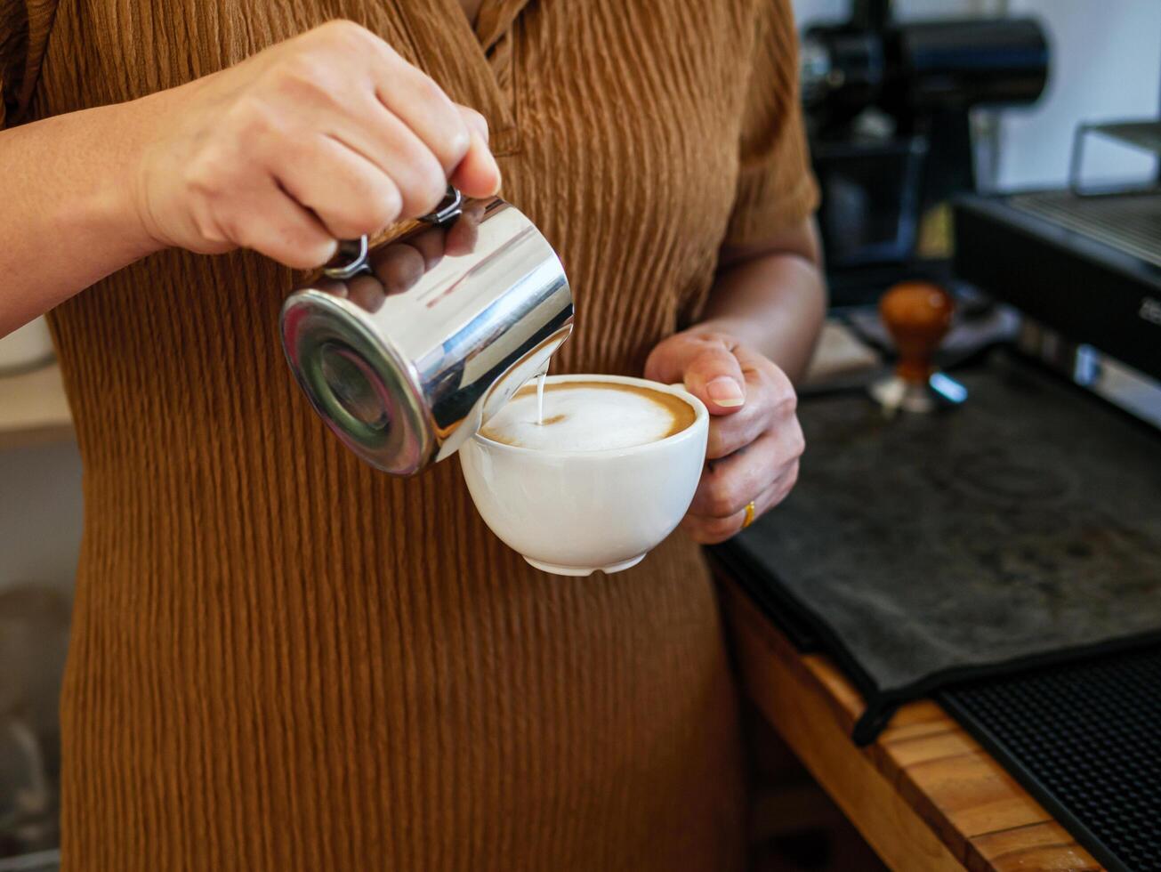 Barista pouring milk into coffee making a cappuccino. Barista making cappuccino,Professional bartender preparing coffee drink photo