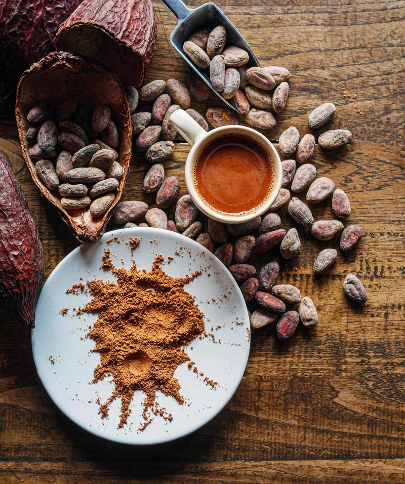 Top view of hot chocolate drink,cocoa drink and natural cocoa powder with brown cocoa beans and dry cacao pod on a vintage wooden table. photo