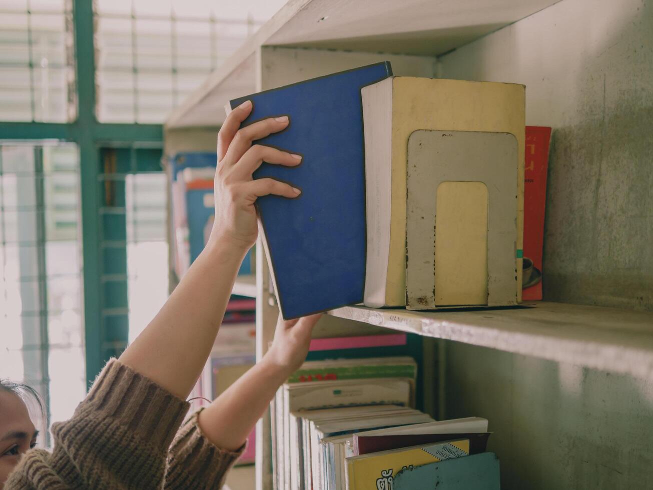 The hands of a woman taking out a book from the bookshelf photo
