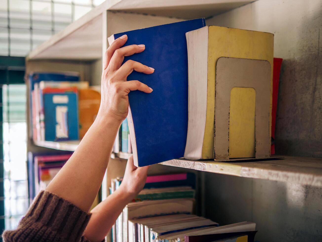 The hands of a woman taking out a book from the bookshelf photo