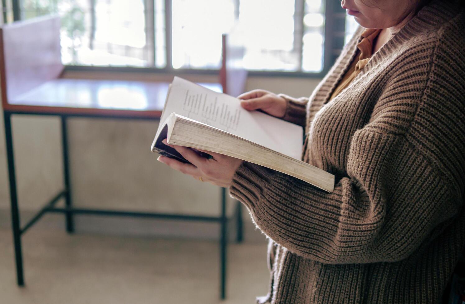 Learning, education Hand of Senior woman standing holding a book in library by the window in the morning, relax and enjoy books. photo