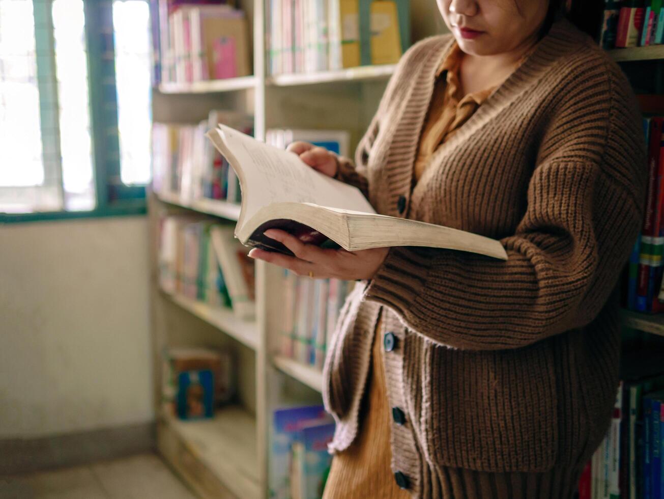 Learning, education Hand of Senior woman standing holding a book in library by the window in the morning, relax and enjoy books. photo