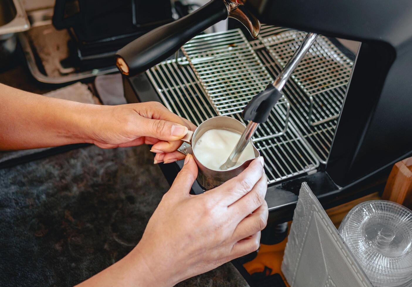 Close-up of Barista hand using high-pressure steam-operated milk frother to prepare a cappuccino and latte coffee milk photo