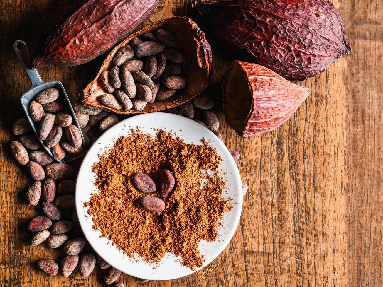 Top view of Natural cocoa powder with brown cocoa beans and dry cacao pod on a vintage wooden table. photo