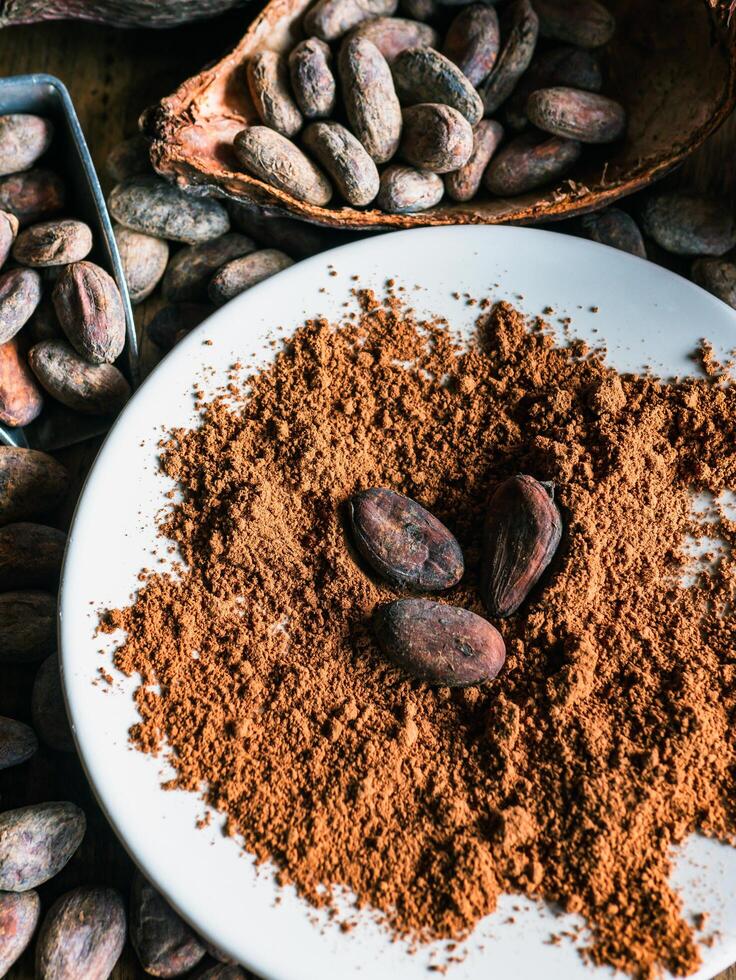 Close-up of Natural cocoa powder with brown cocoa beans and dry cacao pod on a vintage wooden table.Top view photo