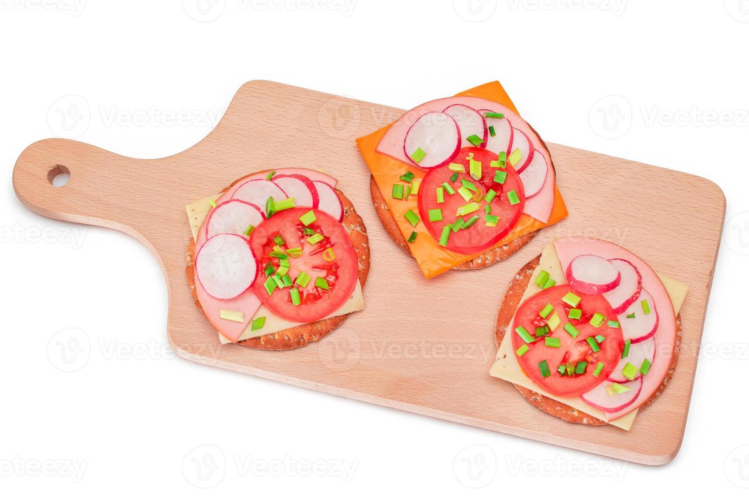 Crispy Cracker Sandwiches with Tomato, Sausage, Cheese, Green Onions and Radish on Cutting Board - Isolated. Easy Breakfast. Quick and Healthy Sandwiches. Crispbread with Tasty Filling - Isolation photo