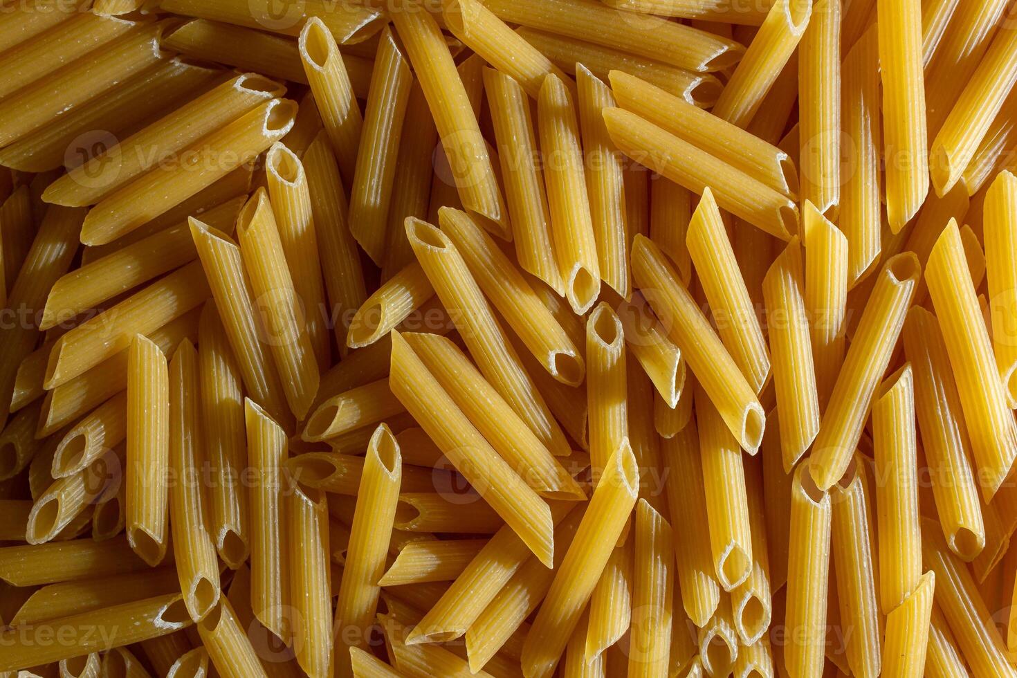 Uncooked Penne Rigate Pasta. A Culinary Canvas of Penne Macaroni, Creating a Lively and Textured Background for Gourmet Cooking. Dry Pasta. Raw Macaroni - Top View, Flat Lay photo
