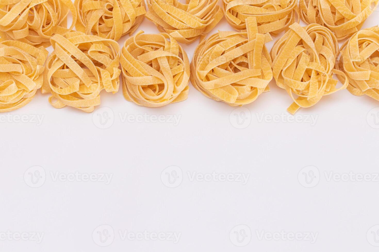 Classic Italian Raw Egg Fettuccine with Copy Spase on White Background. Dry Twisted Uncooked Pasta. Italian Culture and Cuisine. Raw Golden Macaroni Pattern photo