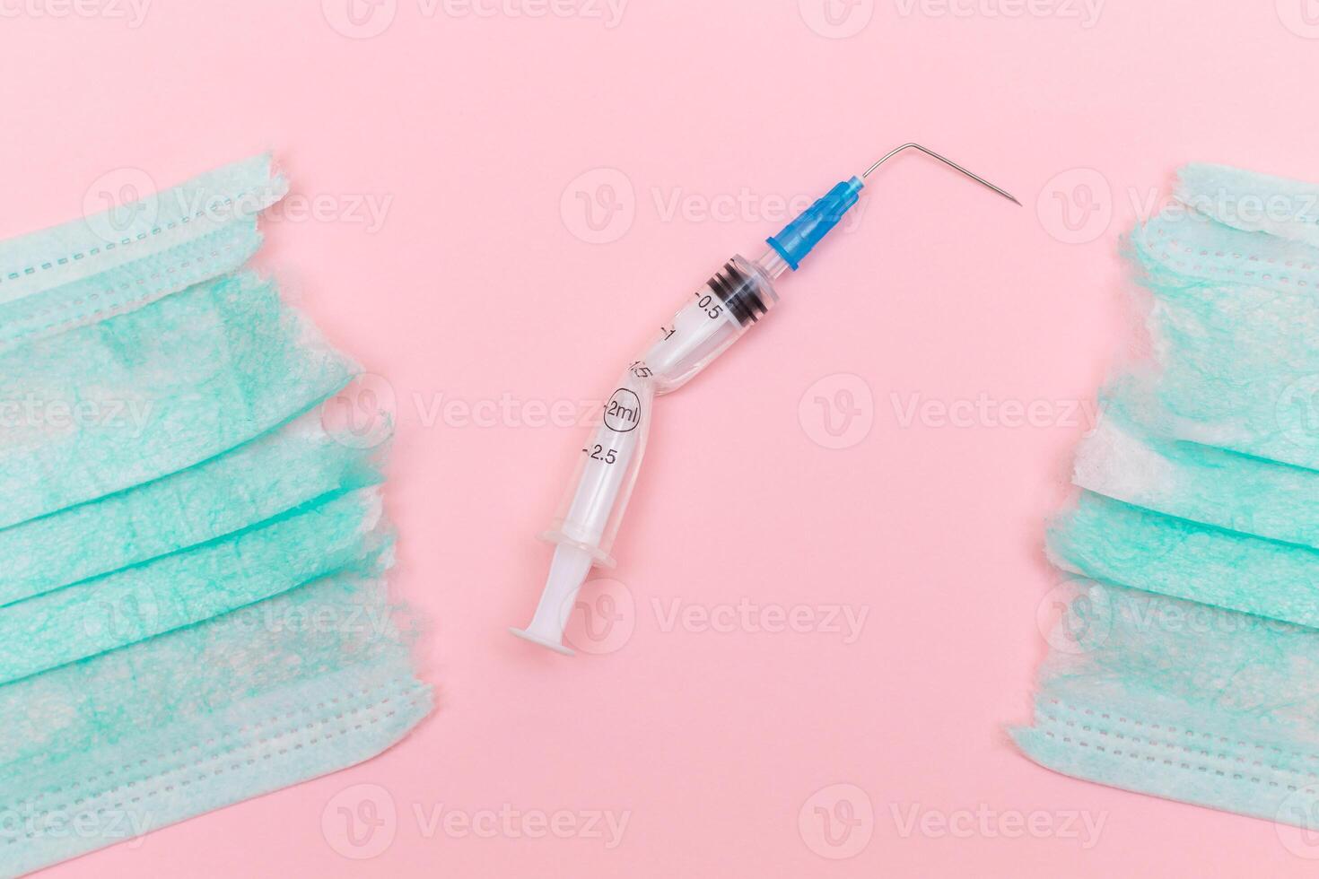 Anti Vaccine Movement and Anti Mask Concept - Broken Medical Syringe and Green Torn Medical Face Mask on the Pink Background. Pandemic and Lockdown End - Top View, Flat Lay photo