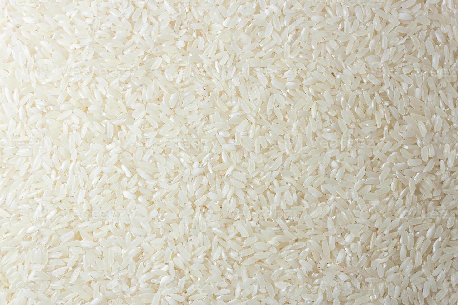 Dry Uncooked White Rice Background - Top View, Flat Lay. Scattered Raw Long Grain Rice. Asian Cuisine and Culture. Healthy Eating Ingredients. Diet Food photo