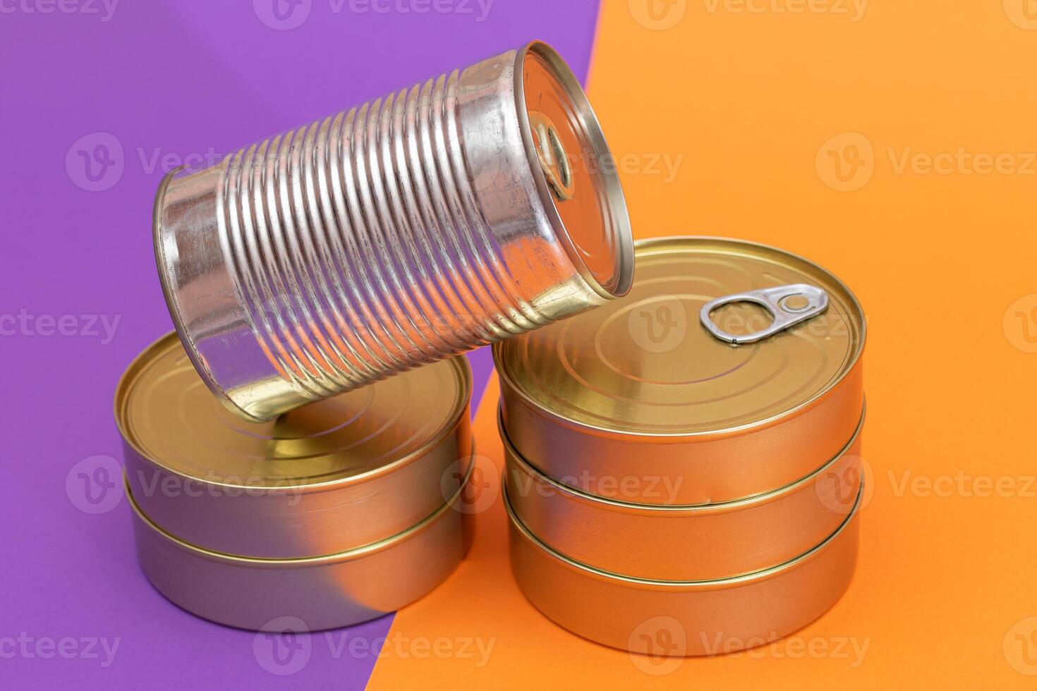 A Group of Stacked Tin Cans with Blank Edges on Split Orange and Violet Background. Canned Food. Different Aluminum Cans for Safe and Long Term Storage of Food. Steel Sealed Food Storage Containers photo