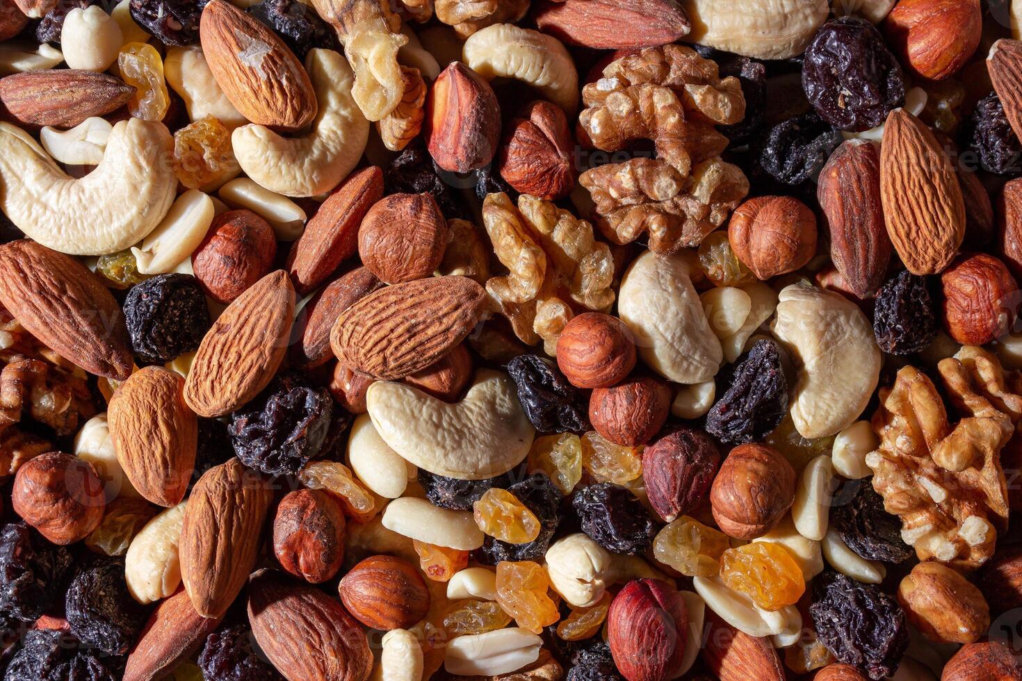 Mixed Nuts. Almonds, Walnuts, Cashews, Peanuts, Hazelnuts, Dried Prunes and Raisins. Different Nut Mix. Background from Various Nuts and Dried Fruits photo