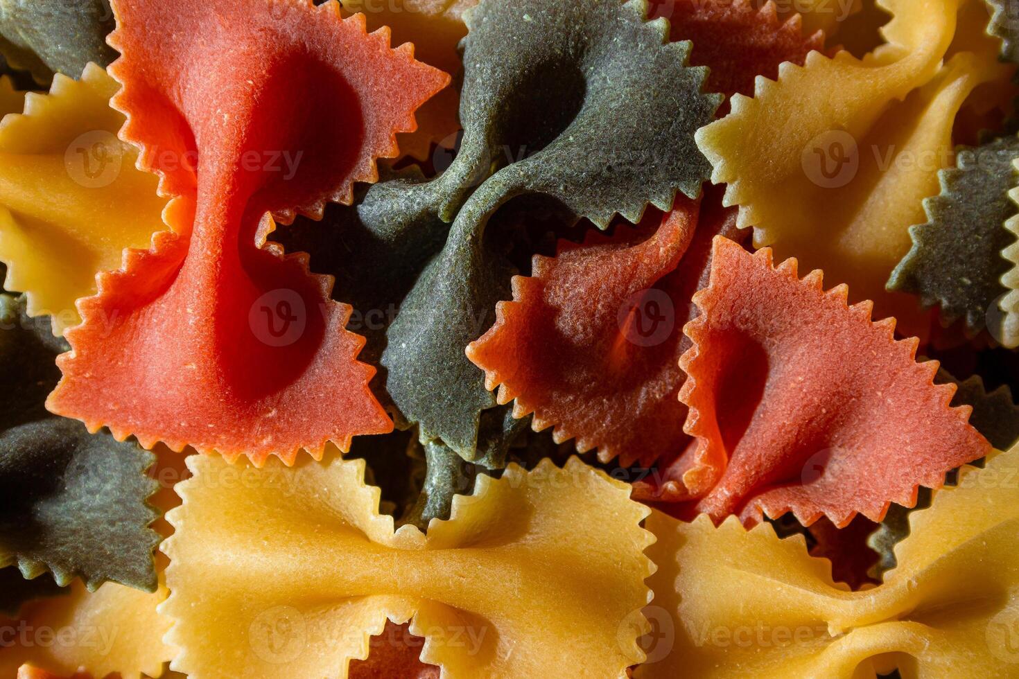 Uncooked Vibrant Colored Farfalle Pasta. A Culinary Canvas of Multicolored Bow-Tie Macaroni, Creating a Lively and Textured Background for Gourmet Cooking Enthusiasts. Colored Dry Pasta. Raw Macaroni photo