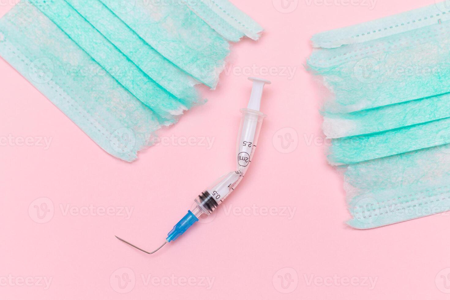 Anti Vaccine Movement and Anti Mask Concept - Broken Medical Syringe and Green Torn Medical Face Mask on the Pink Background. Pandemic and Lockdown End - Top View, Flat Lay photo